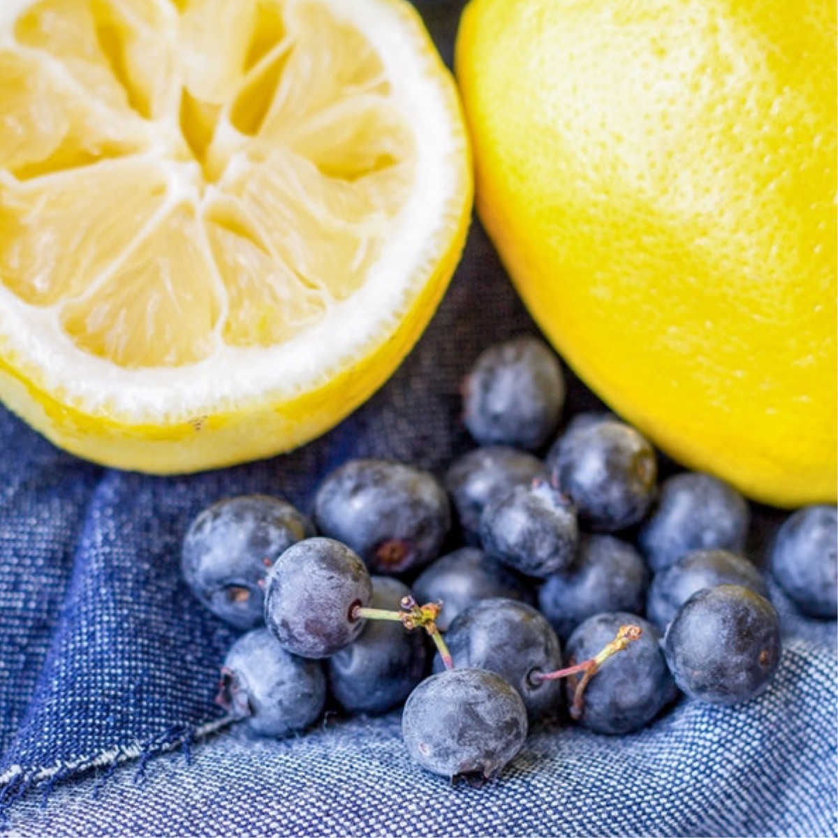 Close-up of blueberries and two halves of an orange on a jeans fabric